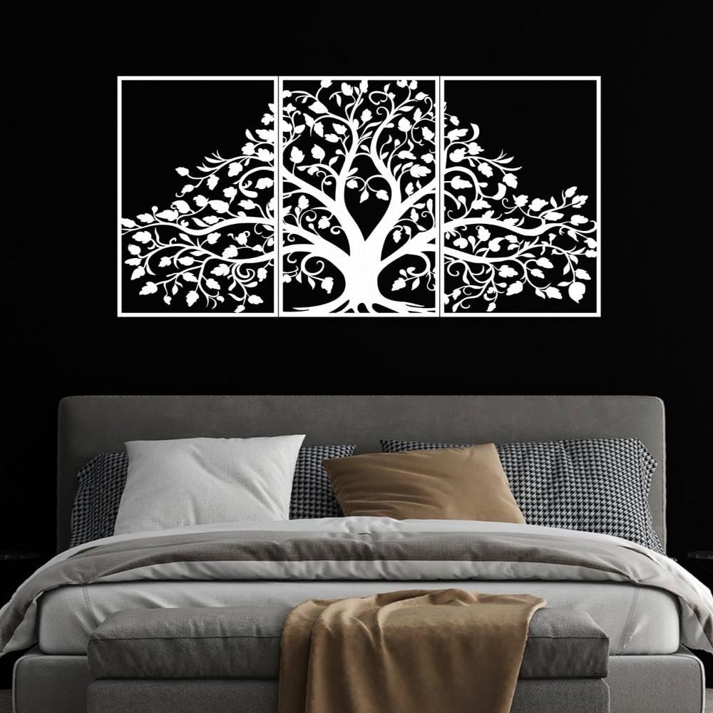 Three-piece white metal wall art featuring a life tree with intricate branches and leaves, mounted on a black wall above a modern bed. The bed is styled with gray and houndstooth-patterned pillows, white bedding, and a beige throw blanket, creating a striking contrast.
