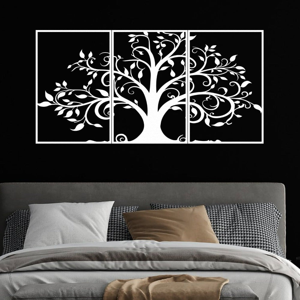 Three-piece white metal wall art featuring an intricate tree design with swirling branches and leaves, mounted on a black wall above a modern bed. The bed is styled with gray bedding, houndstooth-patterned pillows, and beige accent pillows, creating a bold and elegant bedroom look.