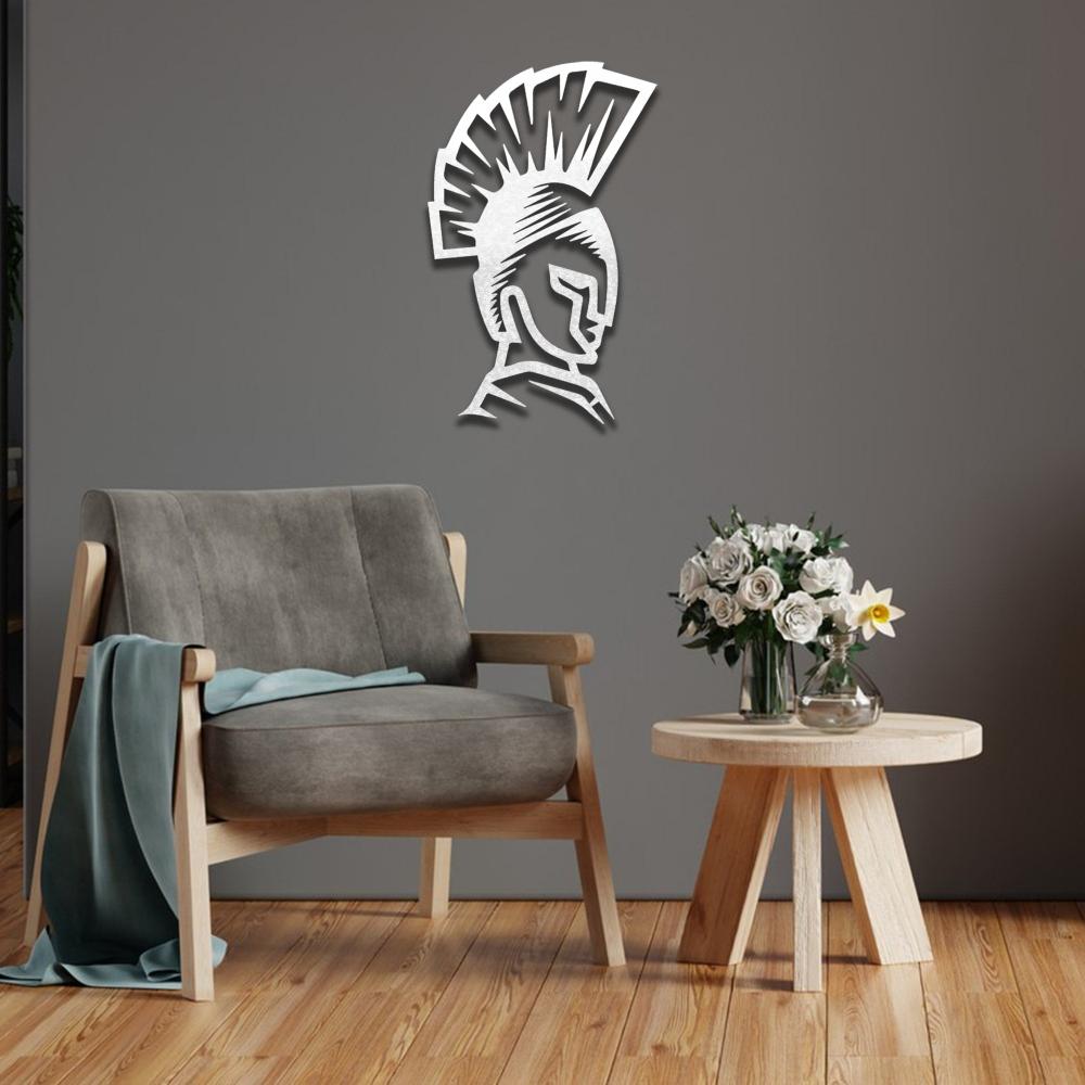 White Spartan helmet metal wall art installed on a dark gray wall, paired with a gray armchair and wooden coffee table.