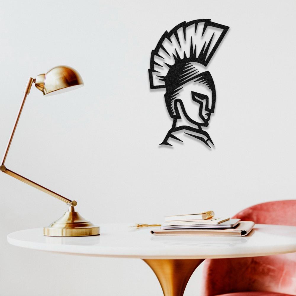 Black Spartan helmet wall art hung above a white workspace table with a brass desk lamp and notebooks for modern office decor.