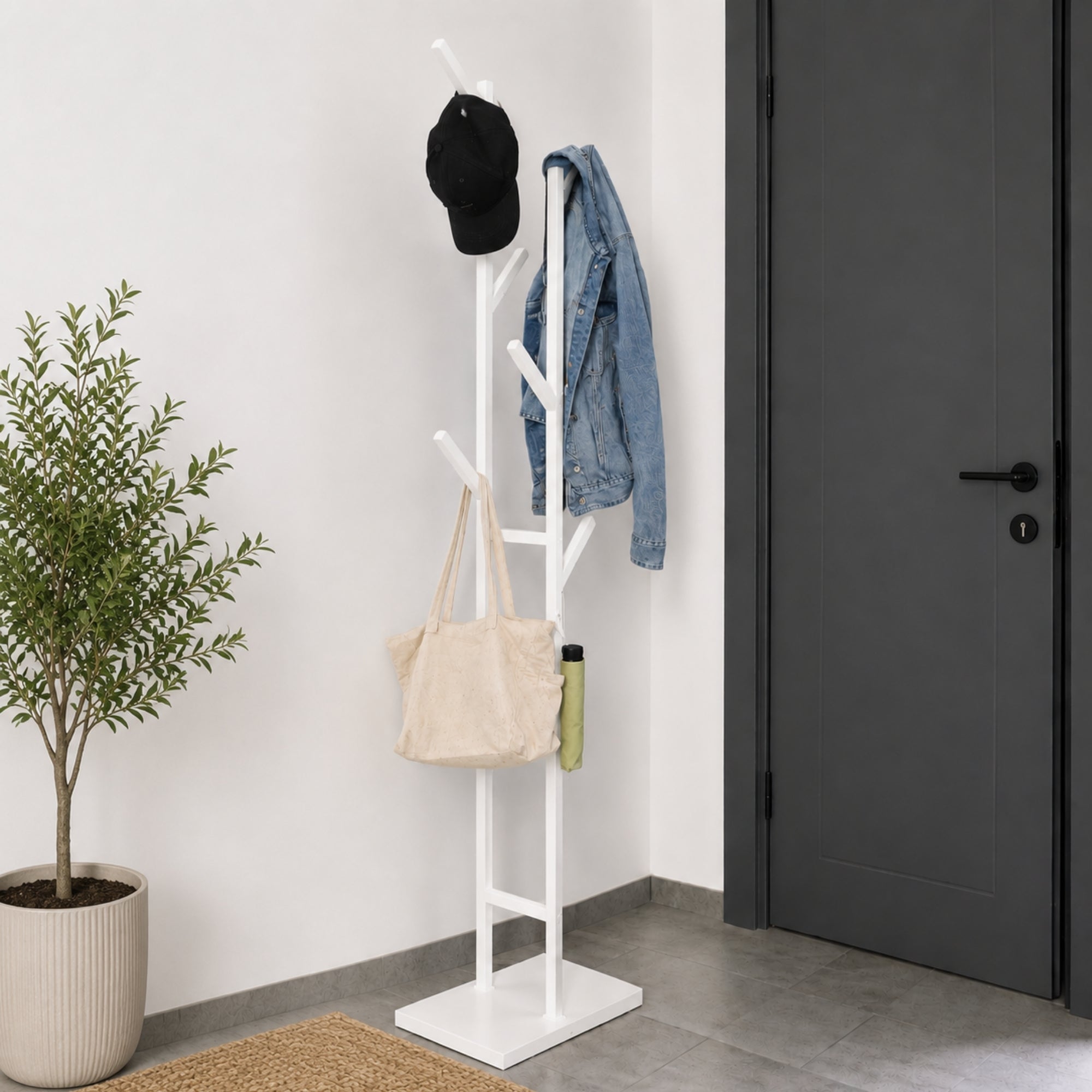 White freestanding 6-hook metal coat rack with jacket, cap, tote bag, and umbrella in a modern entryway.