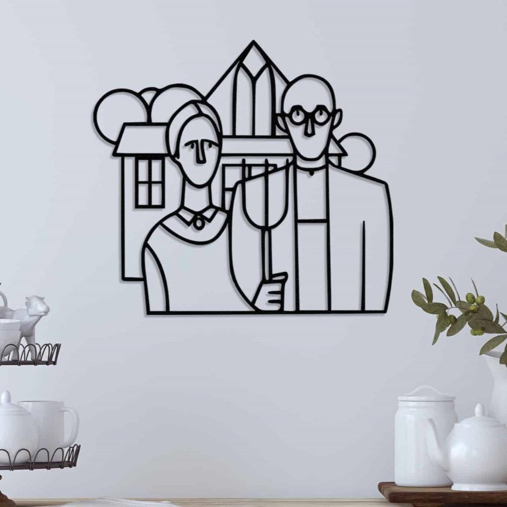 Minimalist black metal wall art depicting the American Gothic farmer couple in front of a geometric farmhouse, displayed on a white wall with simple decor elements in the foreground.