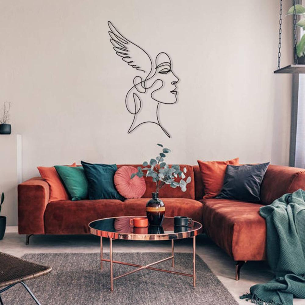 A modern living room with a burnt orange velvet sectional, colorful pillows, and a coffee table, with a winged woman metal wall art centerpiece on the cream wall.