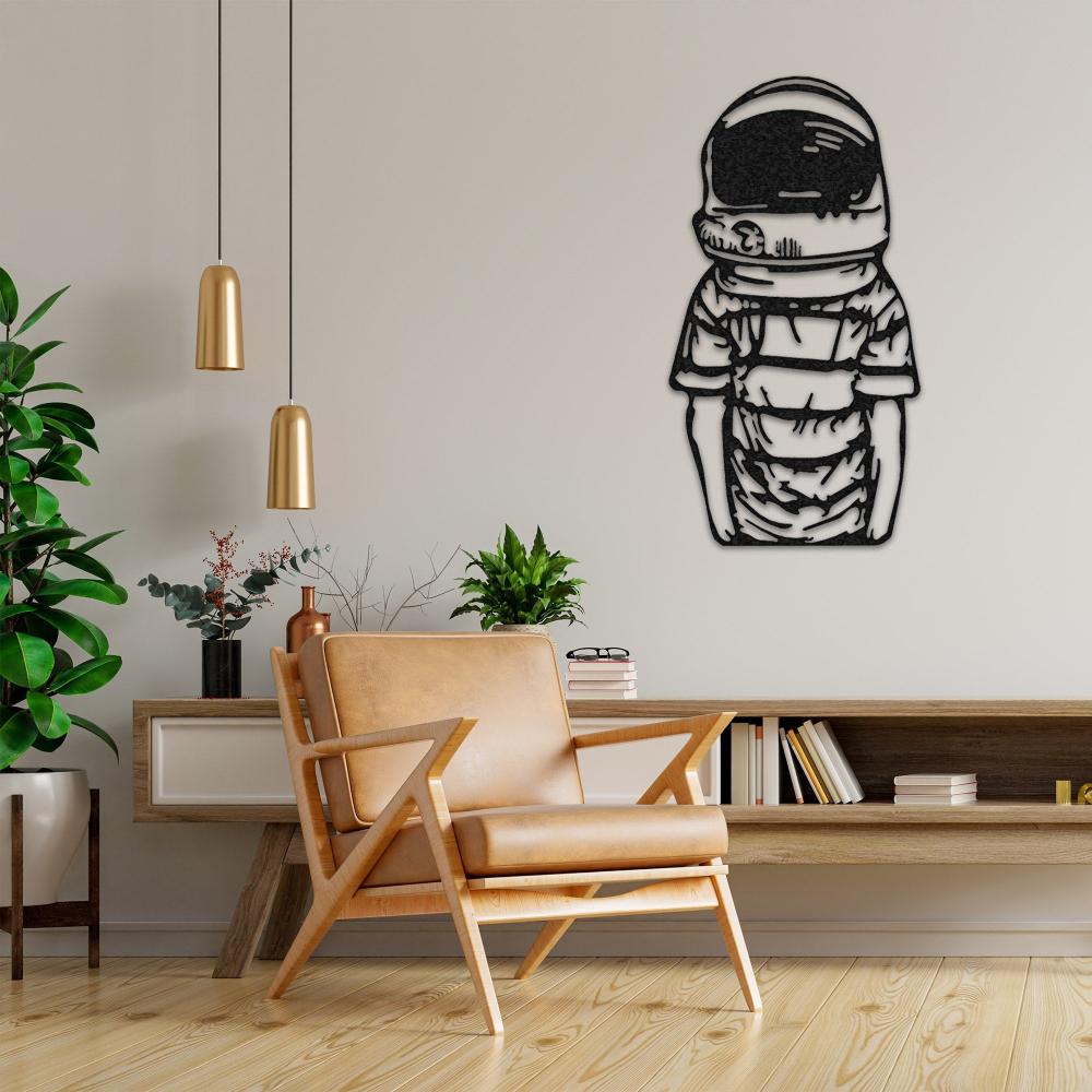 Astronaut metal wall decor featuring a child-like figure in a spacesuit, displayed above a minimalist console table with books and potted plants, next to a modern leather armchair with a light wooden frame.