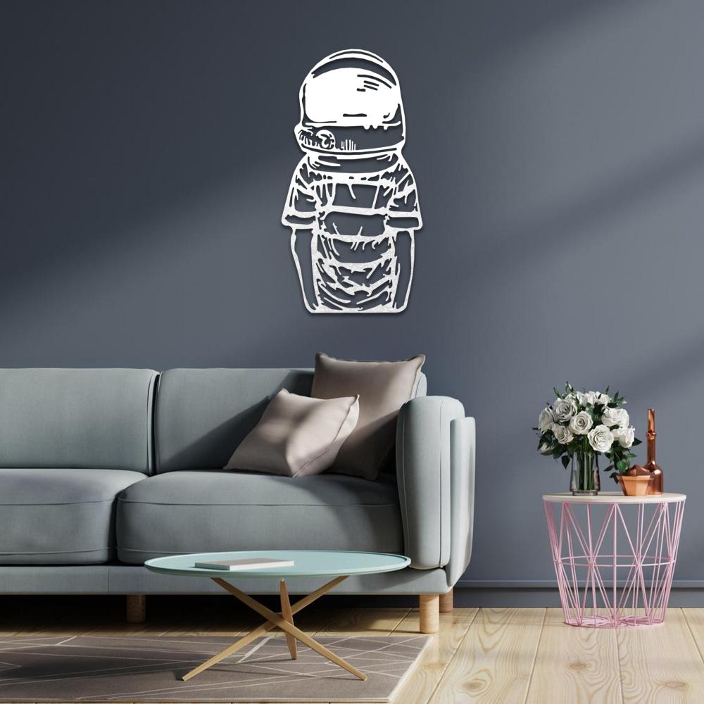 White astronaut metal wall art decor mounted on a dark blue wall in a modern living room featuring a light blue sofa, pink side table with white roses, and a geometric coffee table.