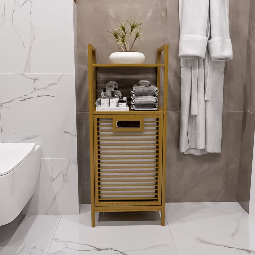Front view of a bamboo bathroom cabinet featuring a tilt-out laundry basket, open shelving with organized towels, and a minimalistic vase with greenery on top