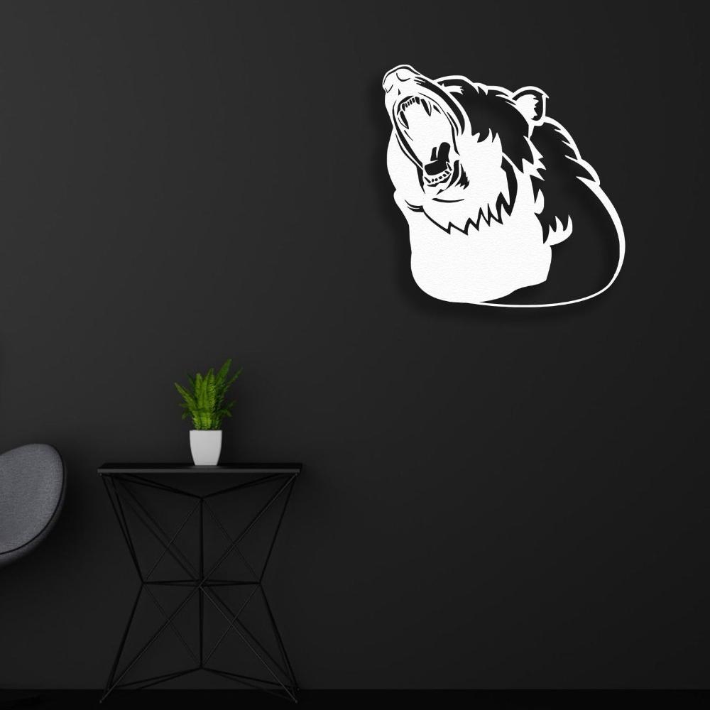 White metal wall art of a roaring bear silhouette mounted on a dark black wall, styled with a minimalist black table, a small green plant in a white pot, and a modern chair.