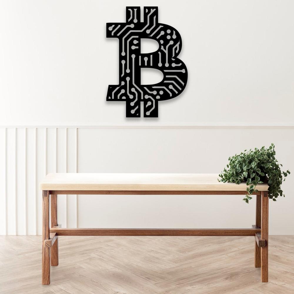 Black Bitcoin-themed wall art with a circuit board pattern, displayed on a neutral wall above a minimalist wooden table with a green plant.