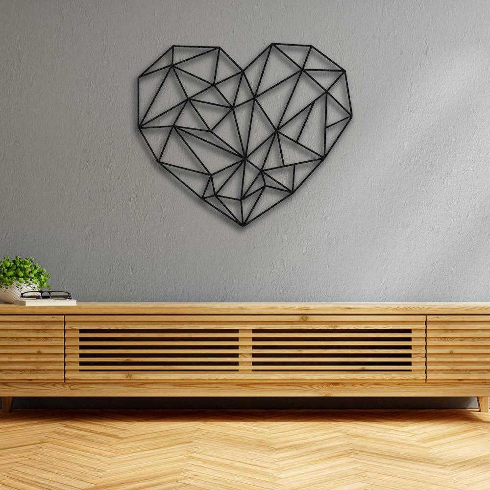 Minimalist geometric heart-shaped metal wall art in black, mounted on a light gray wall above a modern wooden console, with a small plant and a pair of glasses for decor.