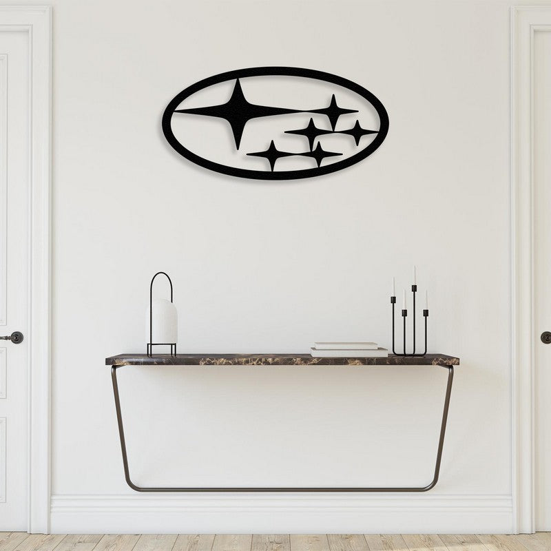 Black metal Subaru car logo wall art mounted on a white wall above a modern black marble console table with a sleek metal frame. The console is styled with a minimalist lantern, stacked books, and a black candle holder, creating an elegant and contemporary ambiance.