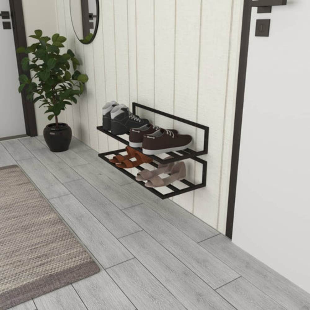 A side view of a black wall-mounted shoe rack with two tiers, neatly holding various shoes including boots, sneakers, and heels, placed in a modern entryway with a potted plant and a beige paneled wall.