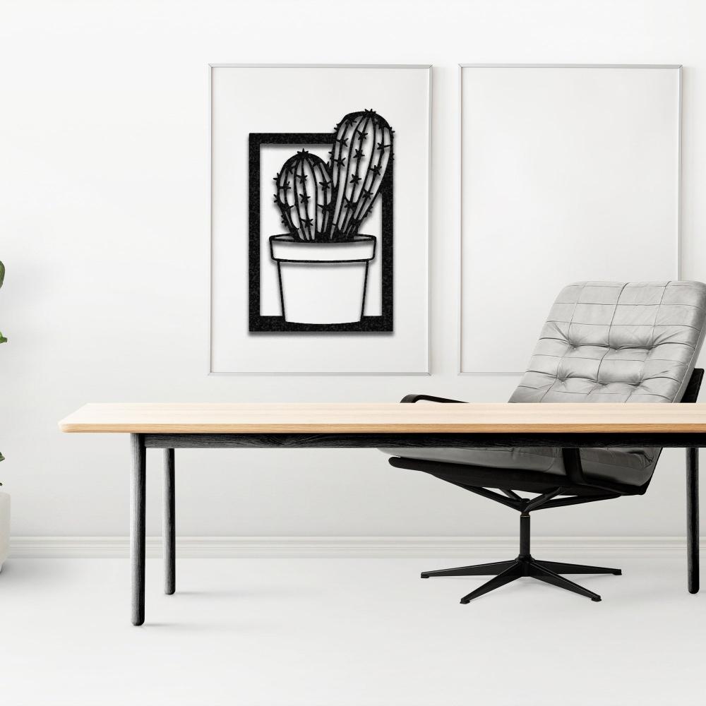 A modern office setup featuring a sleek wooden desk and a gray tufted chair, with a black "Cactus in Vase" metal wall art mounted on a clean white wall.