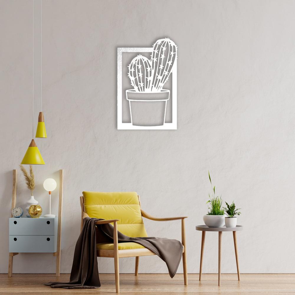 A cozy reading corner with a yellow accent chair, a side table holding small potted plants, and a white "Cactus in Vase" metal wall art mounted on a beige wall.