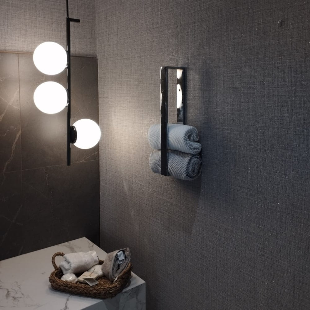 A side angle view of a chrome towel holder with neatly placed rolled towels, highlighting the clean and minimalist design
