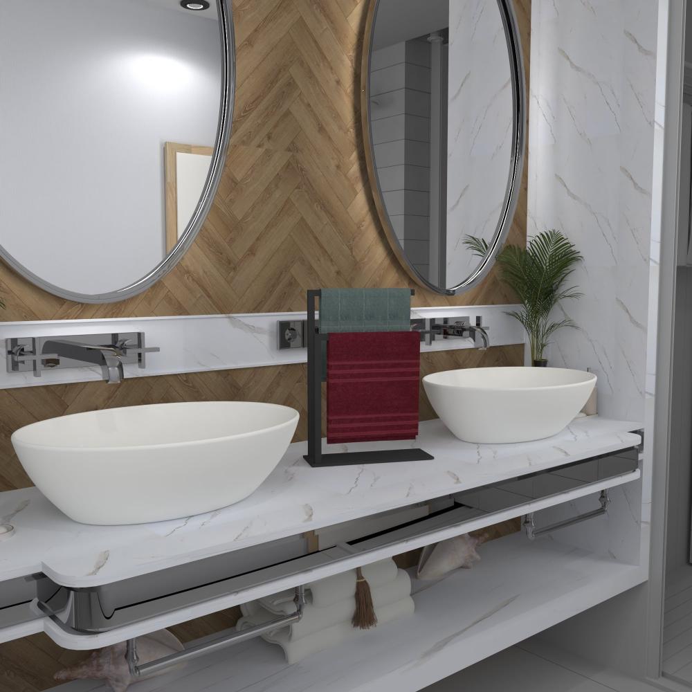 A black countertop towel holder with a modern design displayed on a bathroom countertop between two oval mirrors, holding two neatly folded towels in contrasting colors, adding elegance to the decor.