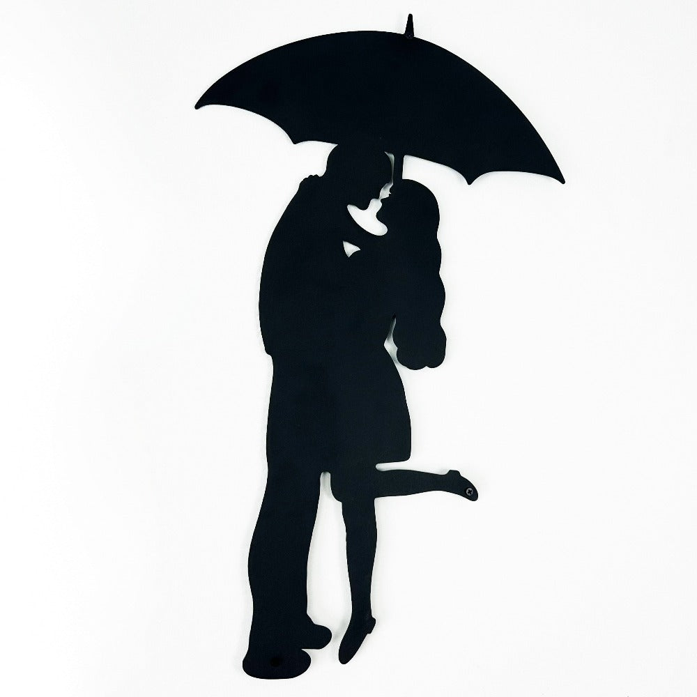 Black silhouette metal wall art of a couple sharing an umbrella in a romantic pose, highlighting intricate detailing and smooth edges.