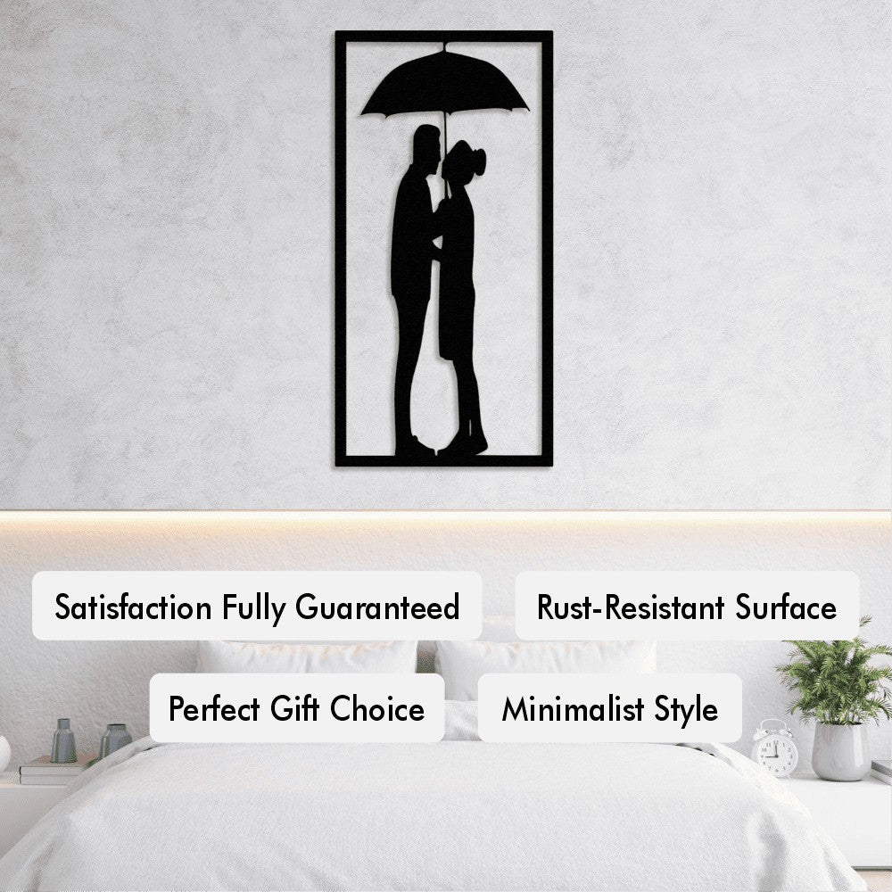 A serene bedroom setting showcasing a black framed metal wall art of a couple standing under an umbrella. The minimalist artwork is placed above the bed with text labels highlighting features like "Satisfaction Fully Guaranteed," "Rust-Resistant Surface," "Perfect Gift Choice," and "Minimalist Style."
