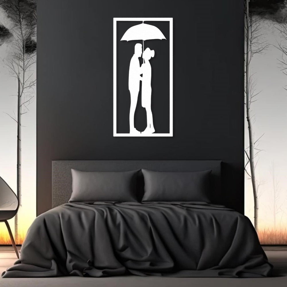 White metal wall art of a couple under an umbrella, elegantly mounted above a dark-themed bed with a minimalist bedroom design.