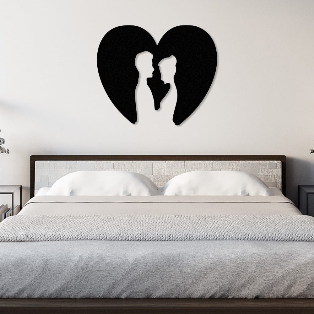 Modern metal wall art featuring a heart-shaped silhouette with a couple inside, mounted above a bed in a minimalist and serene bedroom setting.