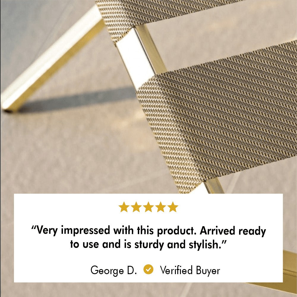 Close-up of the textured brown strap and gold frame of a foldable luggage rack with a customer review reading, "Very impressed with this product. Arrived ready to use and is sturdy and stylish." Verified buyer George D. rates it five stars.