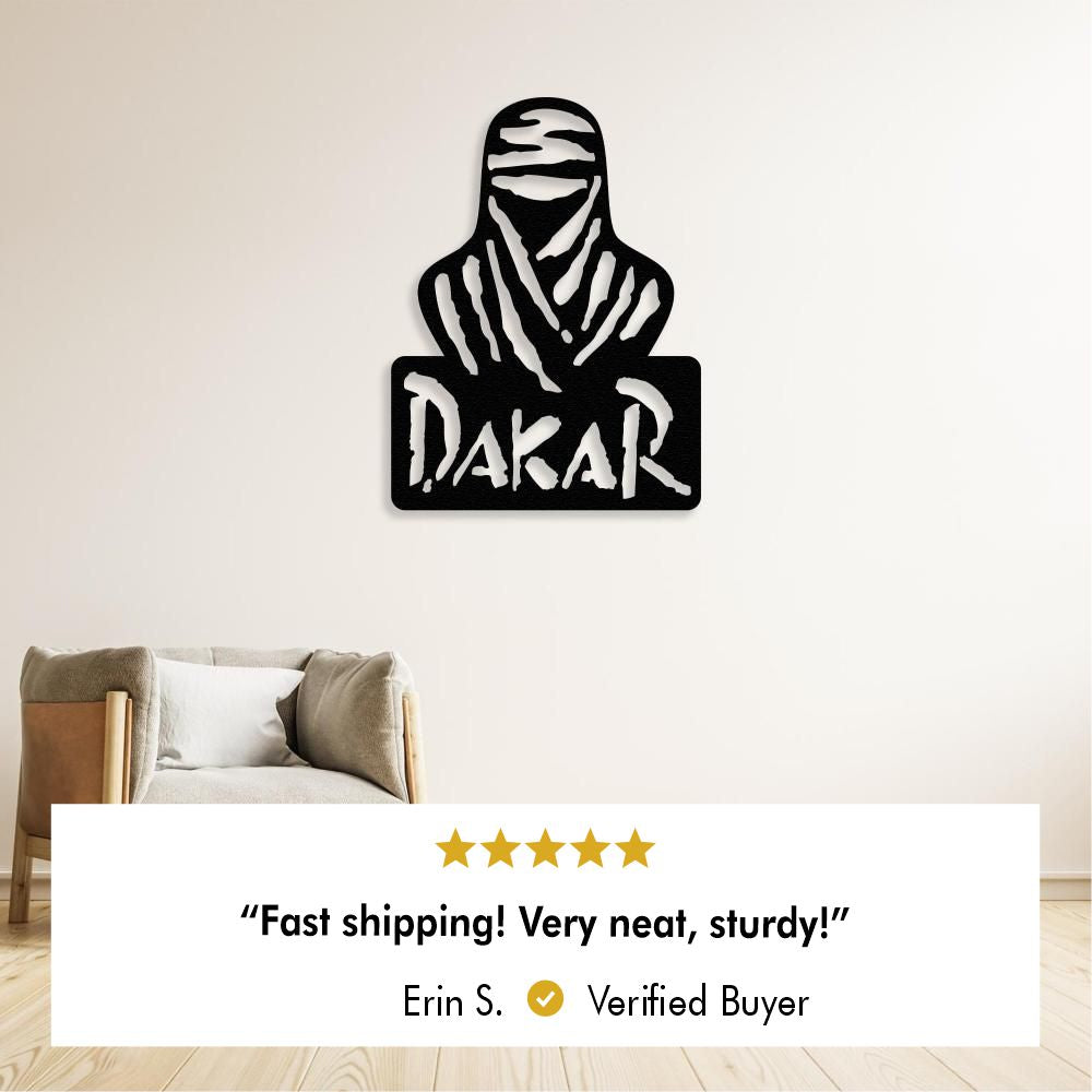 Black metal wall art depicting a veiled figure and the word "Dakar" on a pale wall above an armchair, with a five star review below stating: “Fast shipping! Very neat, sturdy!” by Erin S. Verified Buyer.