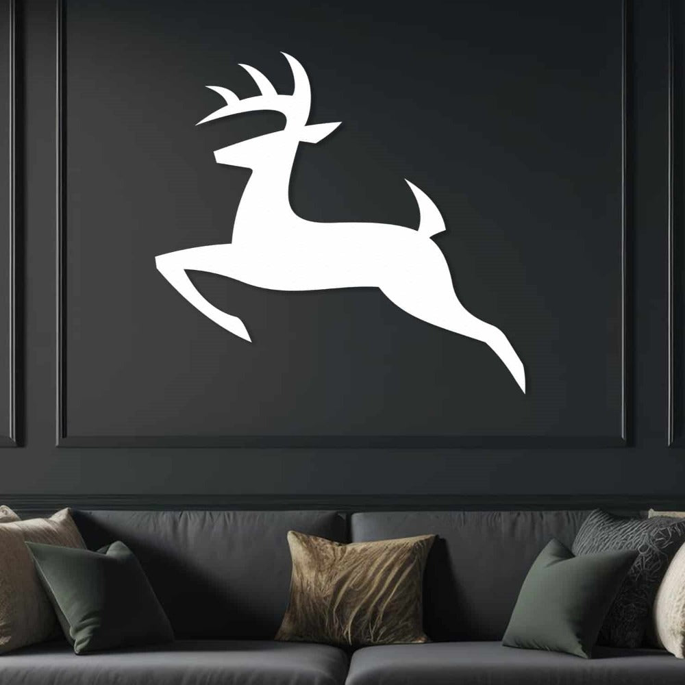 White silhouette metal wall art of a leaping deer mounted on a dark green paneled wall, above a dark leather sofa decorated with green and gold pillows.