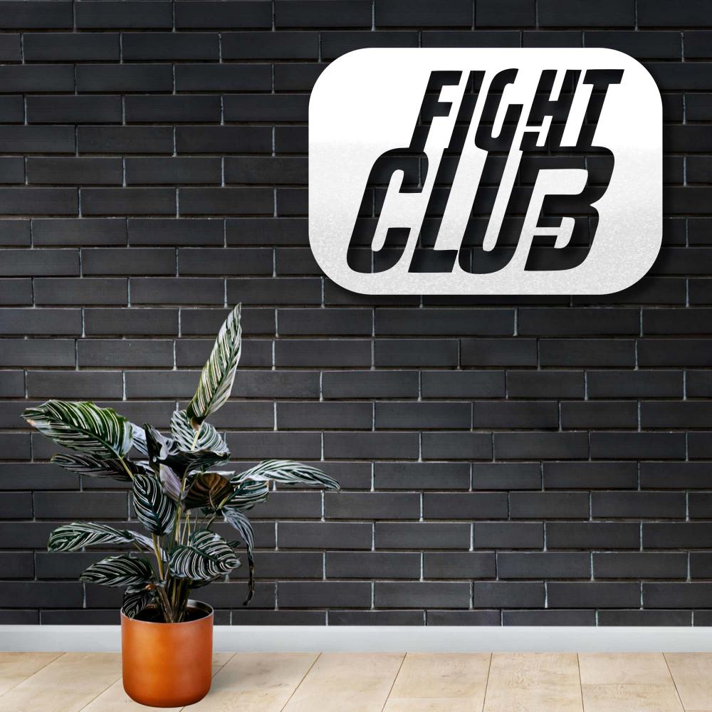 White metal wall art inspired by the "Fight Club" logo, featuring bold typography with a rectangular rounded design, mounted on a sleek dark brick wall, complemented by a potted plant with striped green leaves.