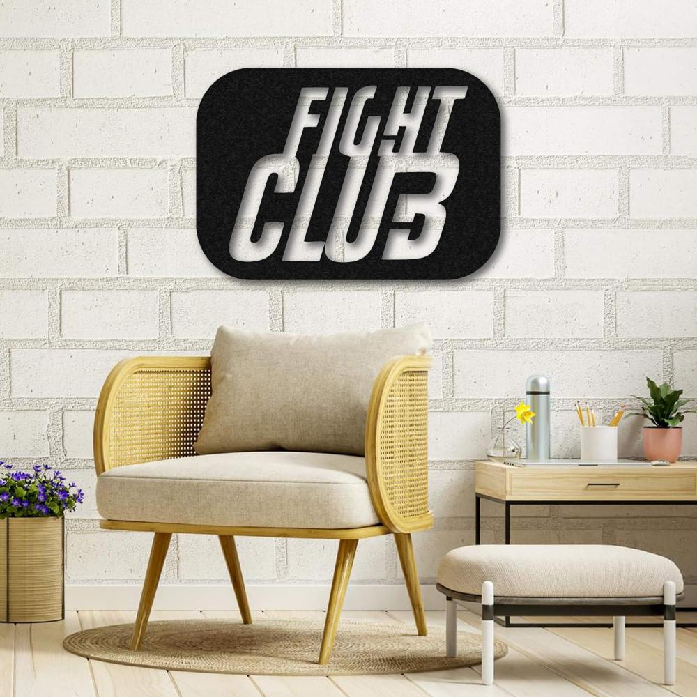 Fight Club-themed metal wall art featuring bold 3D lettering, displayed on a white brick wall above a cozy beige armchair and a wooden side table with decor items in a bright and modern room.