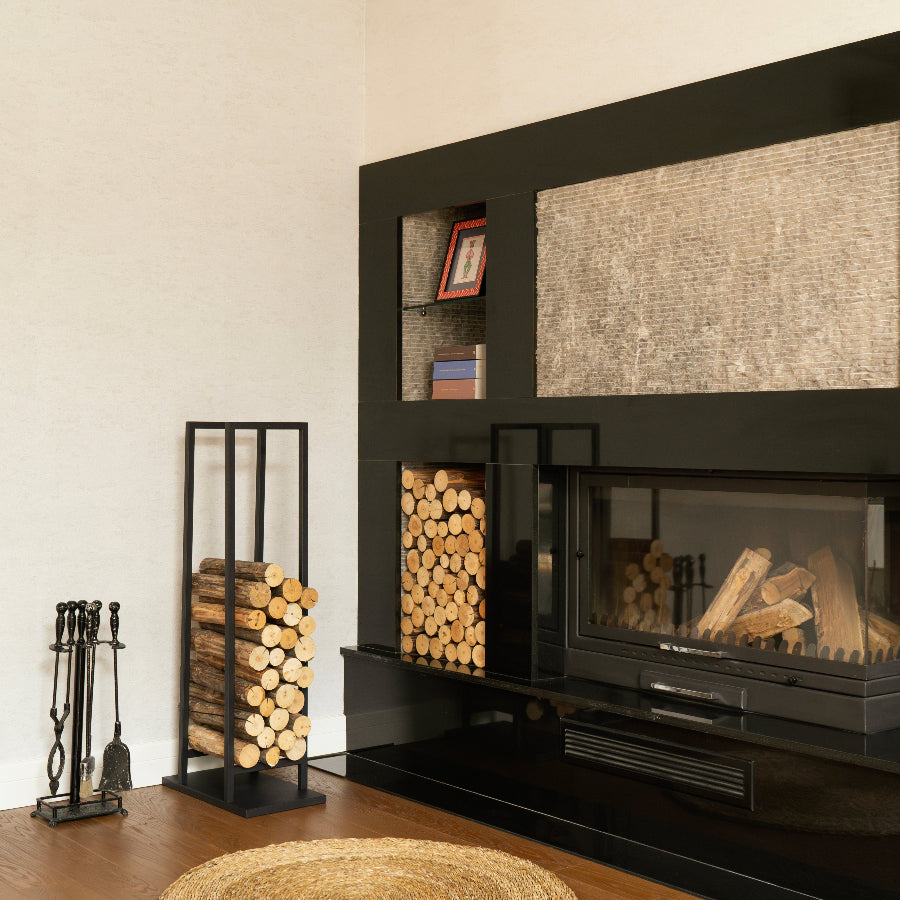 Modern living room with black entertainment console, fireplace, and firewood stand.