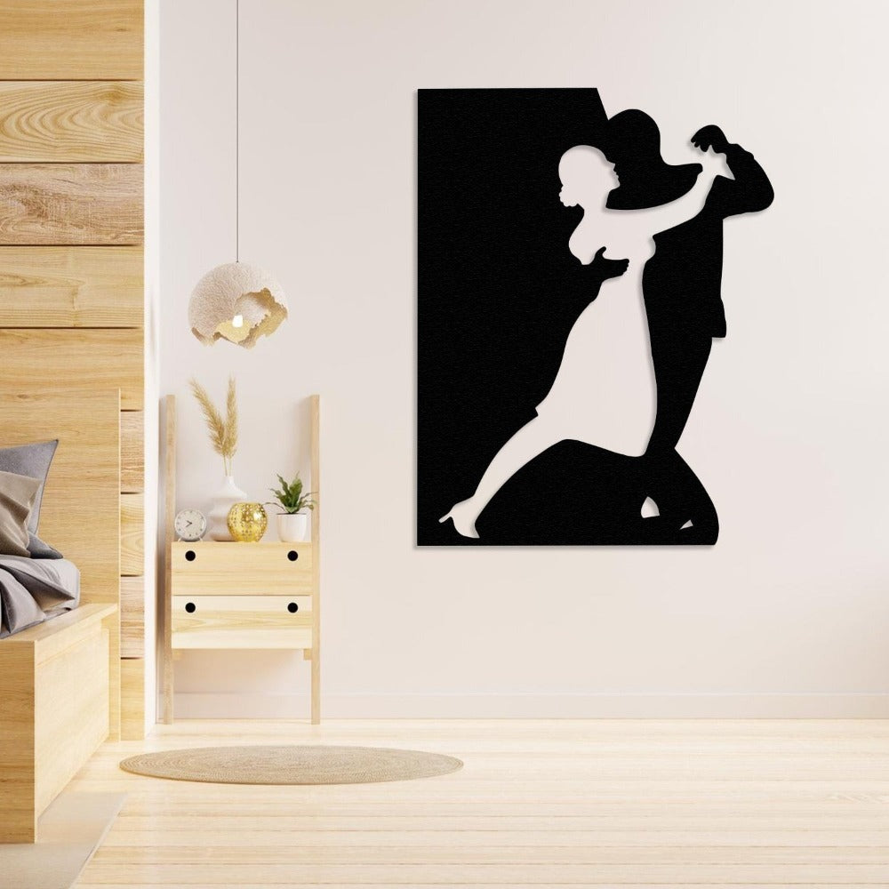 A black metal wall art showing a couple dancing, placed on a beige wall in a cozy bedroom setting with wooden furniture and soft lighting