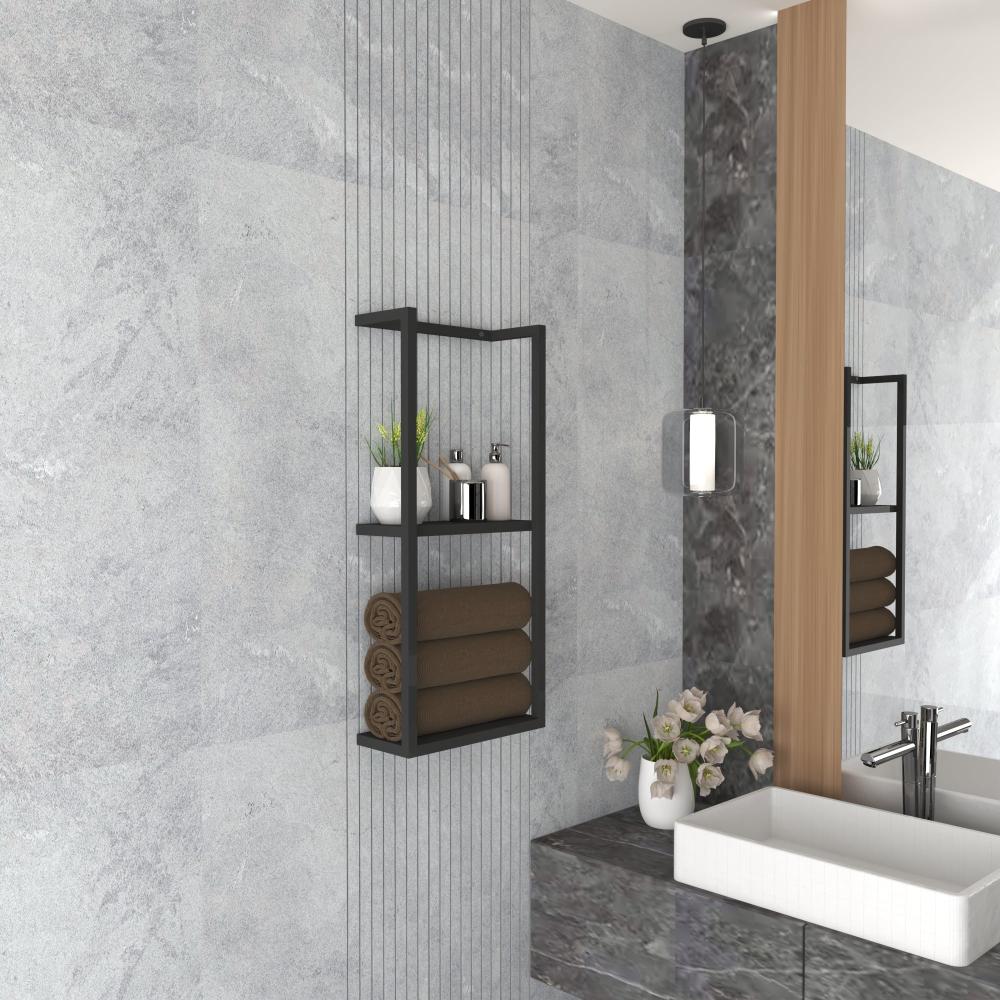 A modern black floating shelf mounted in a contemporary bathroom, holding rolled brown towels and decorative items like a white vase and small plants.