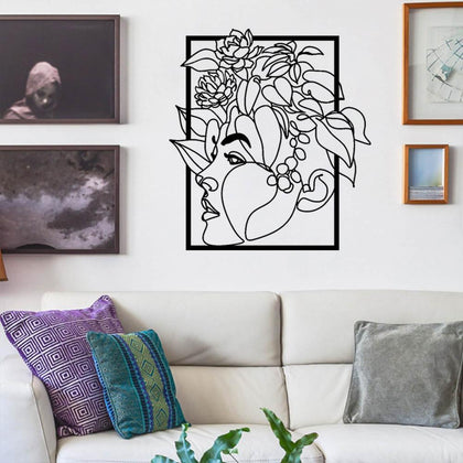 Modern metal wall art of a woman’s face with floral accents, showcased in a living room with white furniture and colorful throw pillows.