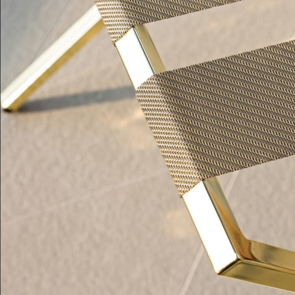 Close-up view of the textured brown fabric straps and gold frame of the luggage rack, highlighting the premium craftsmanship and materials