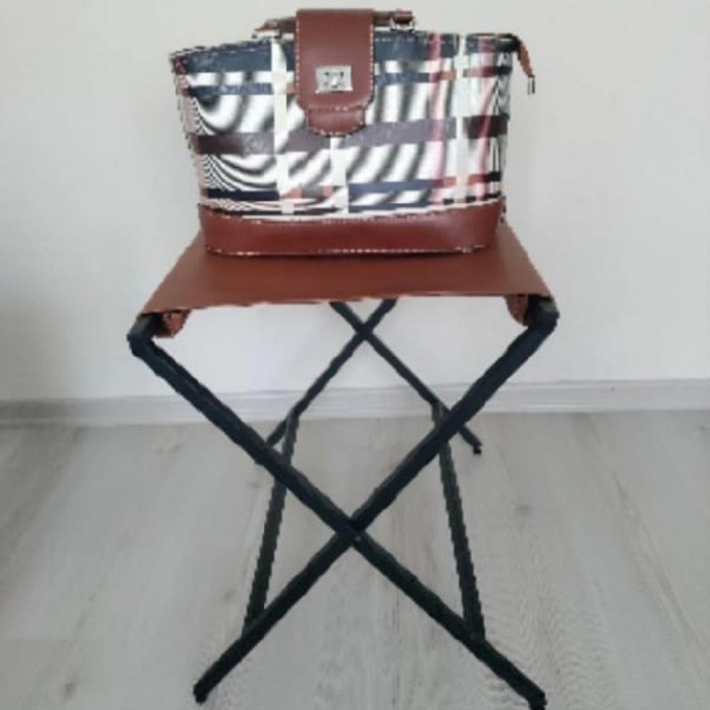 A plaid handbag displayed on a foldable suitcase rack with sleek black metal legs and a genuine leather top, showcasing its functionality and style