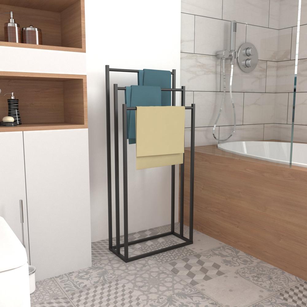 A modern free-standing towel rack with a sleek black metal frame, holding towels in a contemporary bathroom setting.