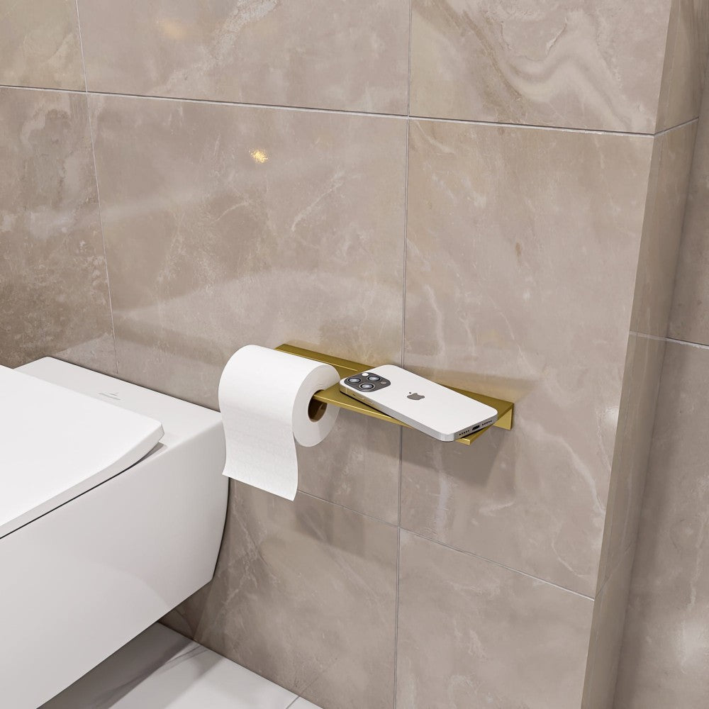 A gold multifunctional bathroom shelf with a toilet paper holder, mounted on beige marble tiles, featuring a smartphone on the shelf and a roll of toilet paper hanging below.