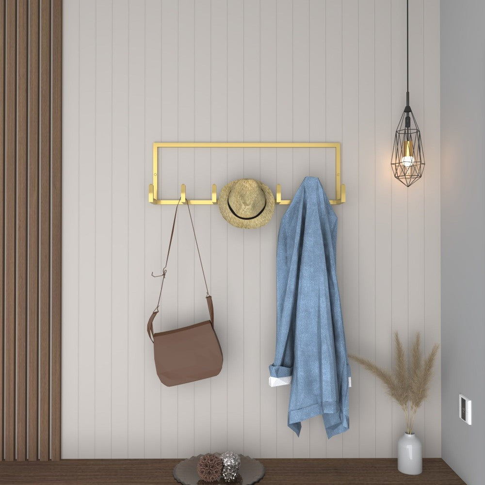 A gold wall-mounted coat rack in a contemporary entryway, styled with a hat, coat, and accessories for a luxurious look.