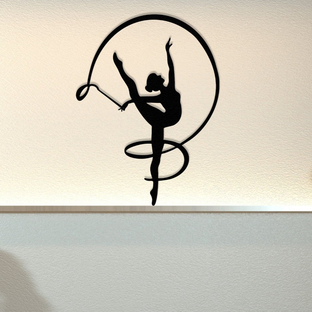 A minimalist room with gymnast girl metal wall art in black, showcasing a graceful ribbon dance pose, illuminated softly against a textured cream wall.