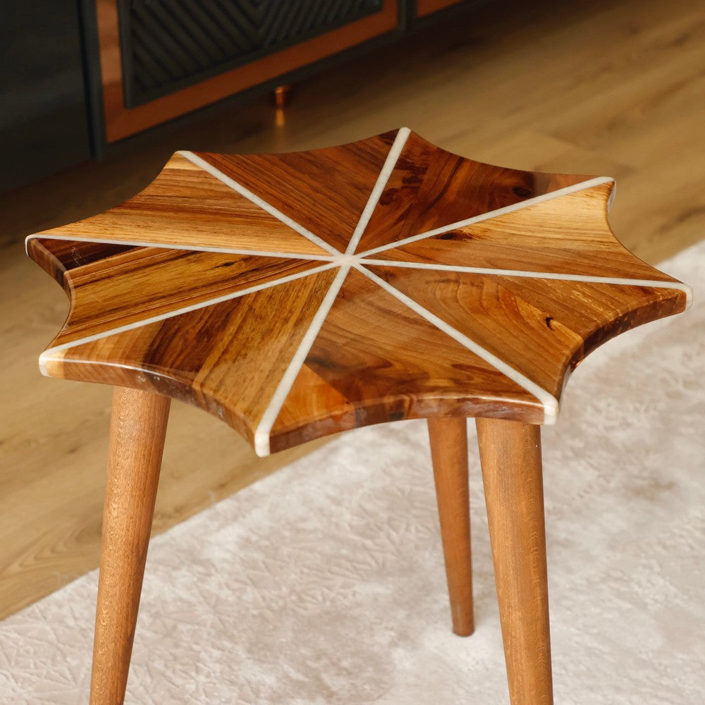 Close-up of a handcrafted wooden side table featuring a unique starburst design with natural wood grain patterns and white resin inlays. The table's elegant craftsmanship showcases a modern and artistic style.