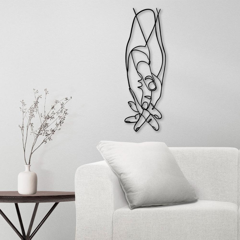 Metal wall art of a couple's hands displayed in a minimalist white living room, accompanied by a small table with a vase.