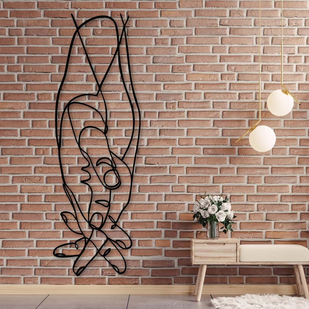 Artistic metal wall decor of intertwined hands, displayed on a textured brick wall, styled with a wooden bench and white roses.