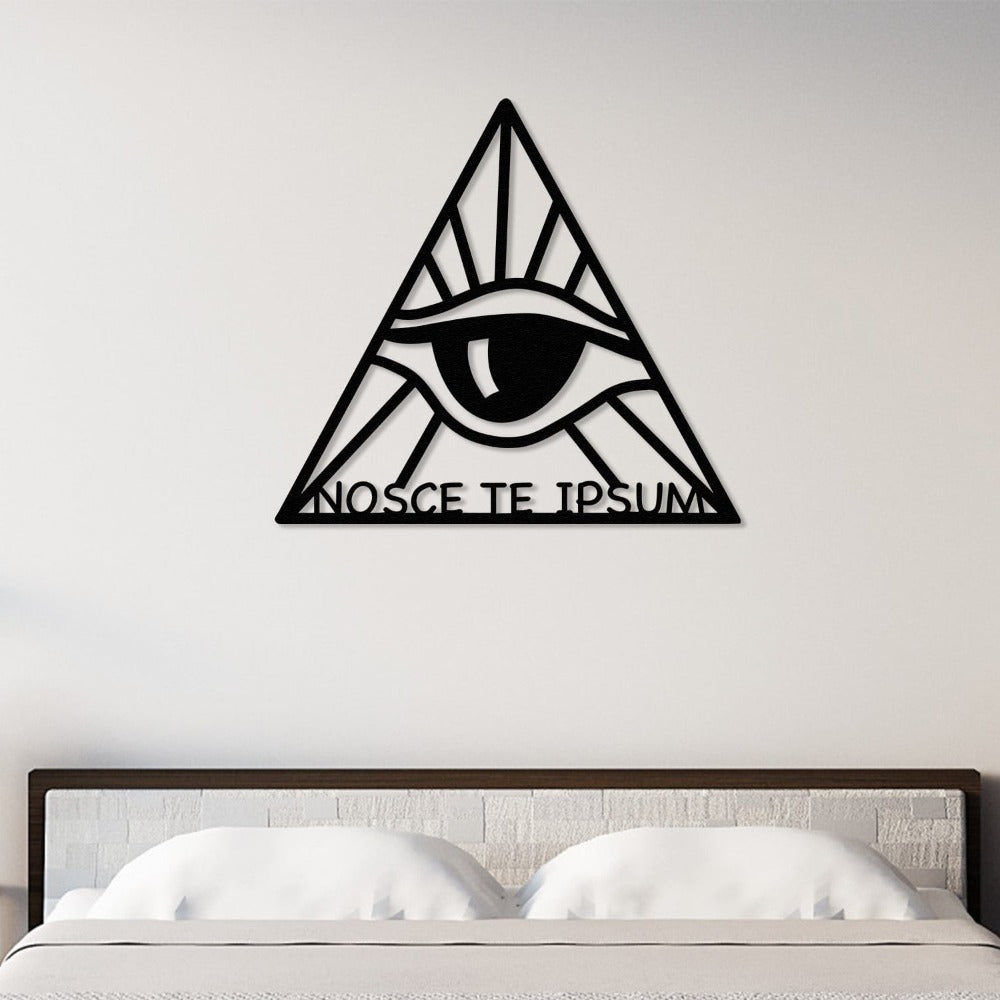 Black triangular metal wall art featuring an eye design and the phrase "Nosce Te Ipsum" (Know Thyself), displayed above a bed with a minimalist headboard and white bedding.