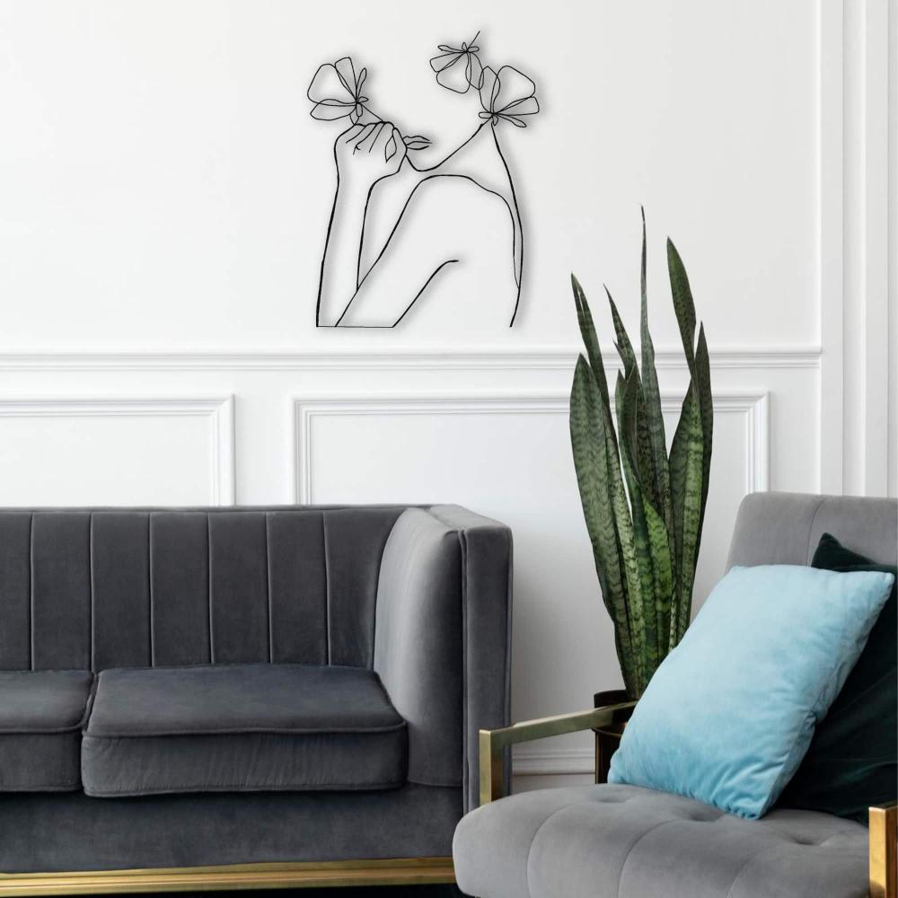 Abstract line art depicting a female figure with flowers, placed above a gray couch with blue and gray decorative cushions, styled in a contemporary room.
