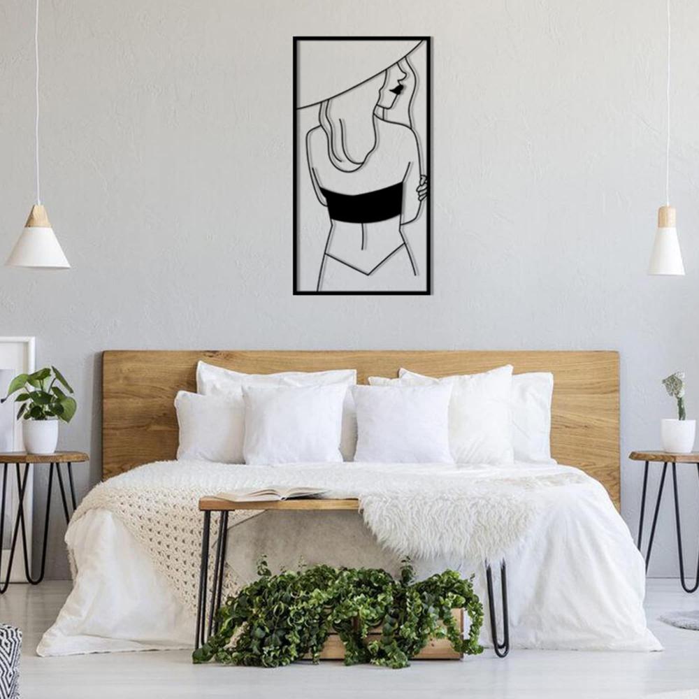 Modern bedroom with a wooden headboard, white linens, and a framed metal wall art of a woman wearing a hat, enhancing the contemporary design.