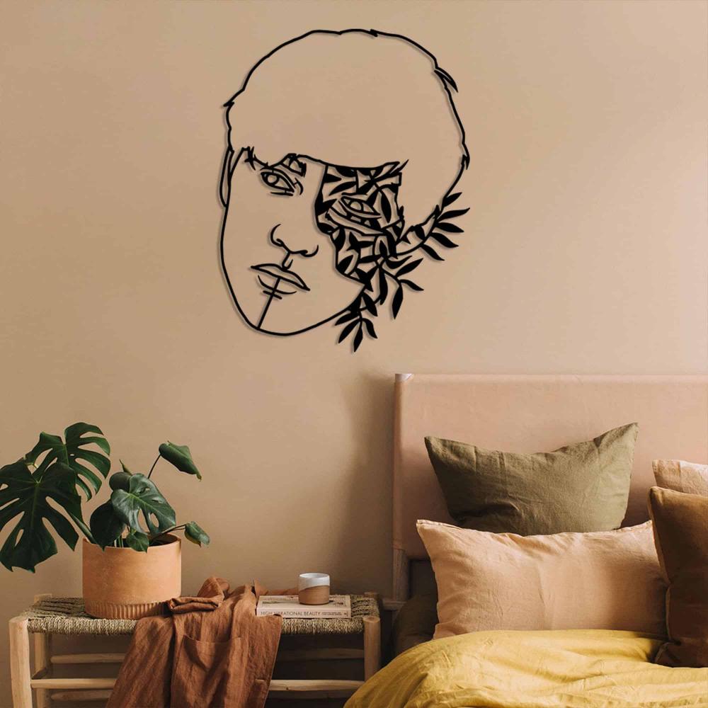 A black metal wall art of a man's face with artistic floral elements, displayed above a bed with earth-toned bedding in a bohemian-style bedroom.