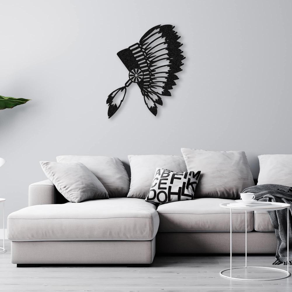 Black metal wall art of an Indian chief's feathered headdress mounted above a stylish grey sectional sofa with modern decor elements.