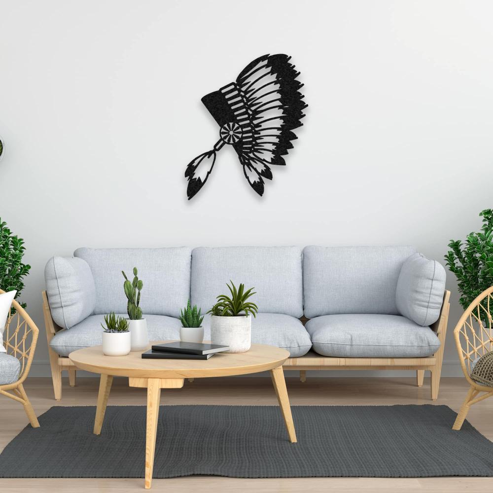 Black metal wall art of an Indian chief's feathered headdress hanging above a light grey sofa with a round wooden coffee table and indoor plants, creating a harmonious living room aesthetic.