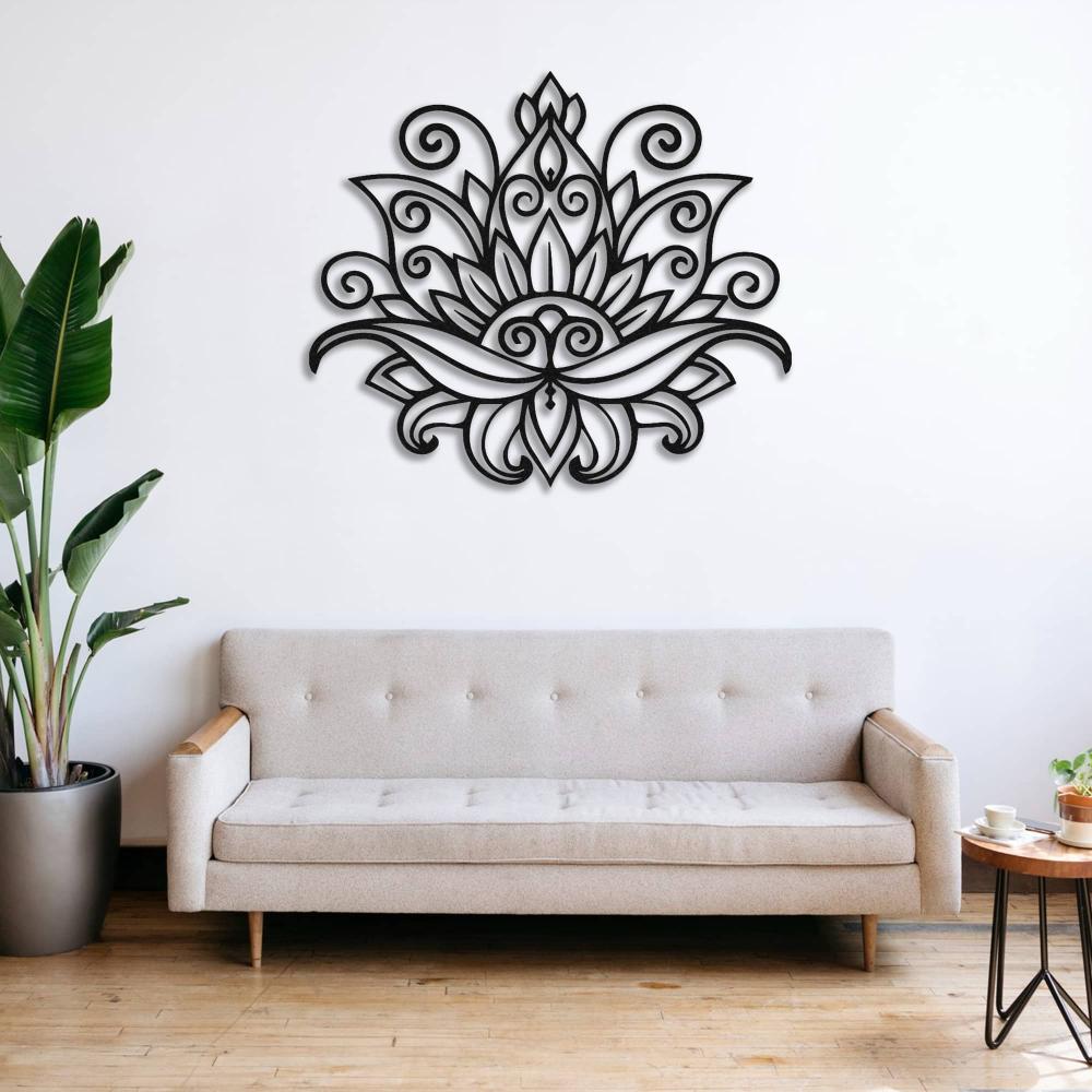 Mandala lotus metal wall art with intricate black floral patterns, mounted on a white wall above a beige tufted sofa in a cozy living space featuring wooden floors and a potted plant.