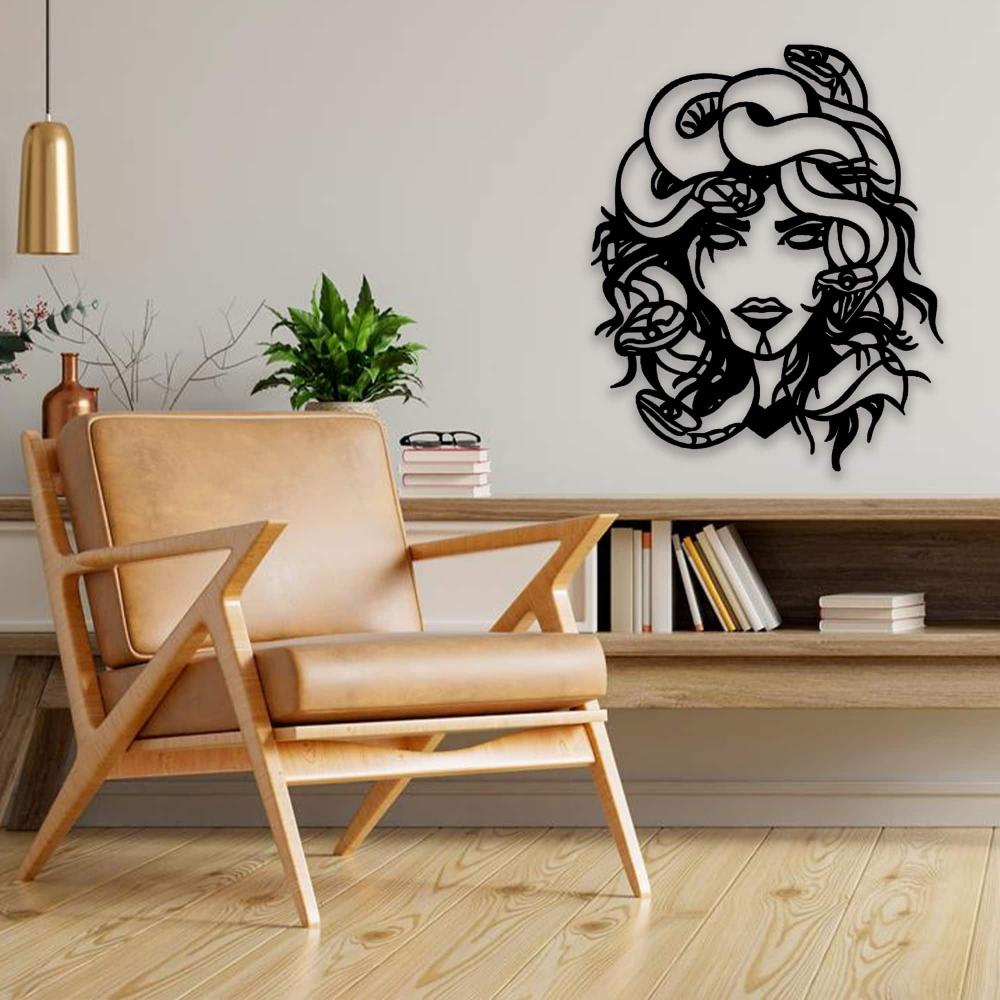 Black Medusa metal wall art mounted on a minimalist living room wall, paired with a tan leather armchair, wooden flooring, and a modern shelf adorned with books and greenery.