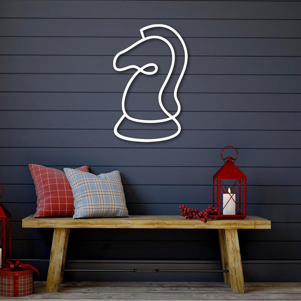 A white minimalist line art of a chess knight mounted on a dark gray shiplap wall, complemented by festive pillows and a red lantern on a wooden bench.